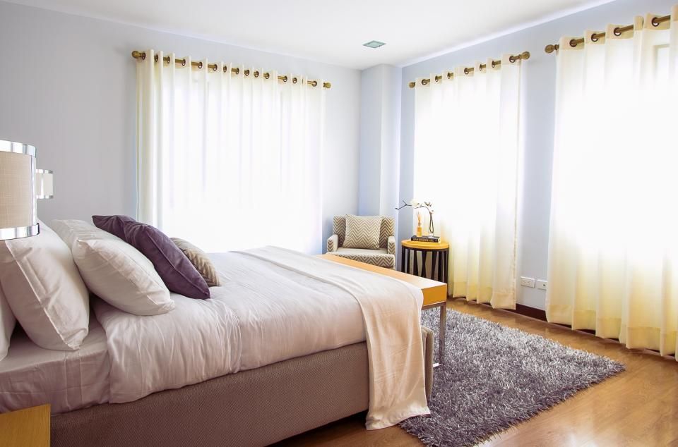 a bright guest room with a made double bed